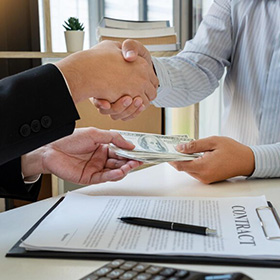 Two People Shaking Hands Over Money